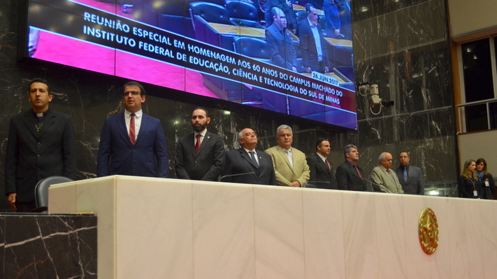 Autoridades estão sentadas à mesa de honra do Auditório da Assembleia de Minas Gerais.