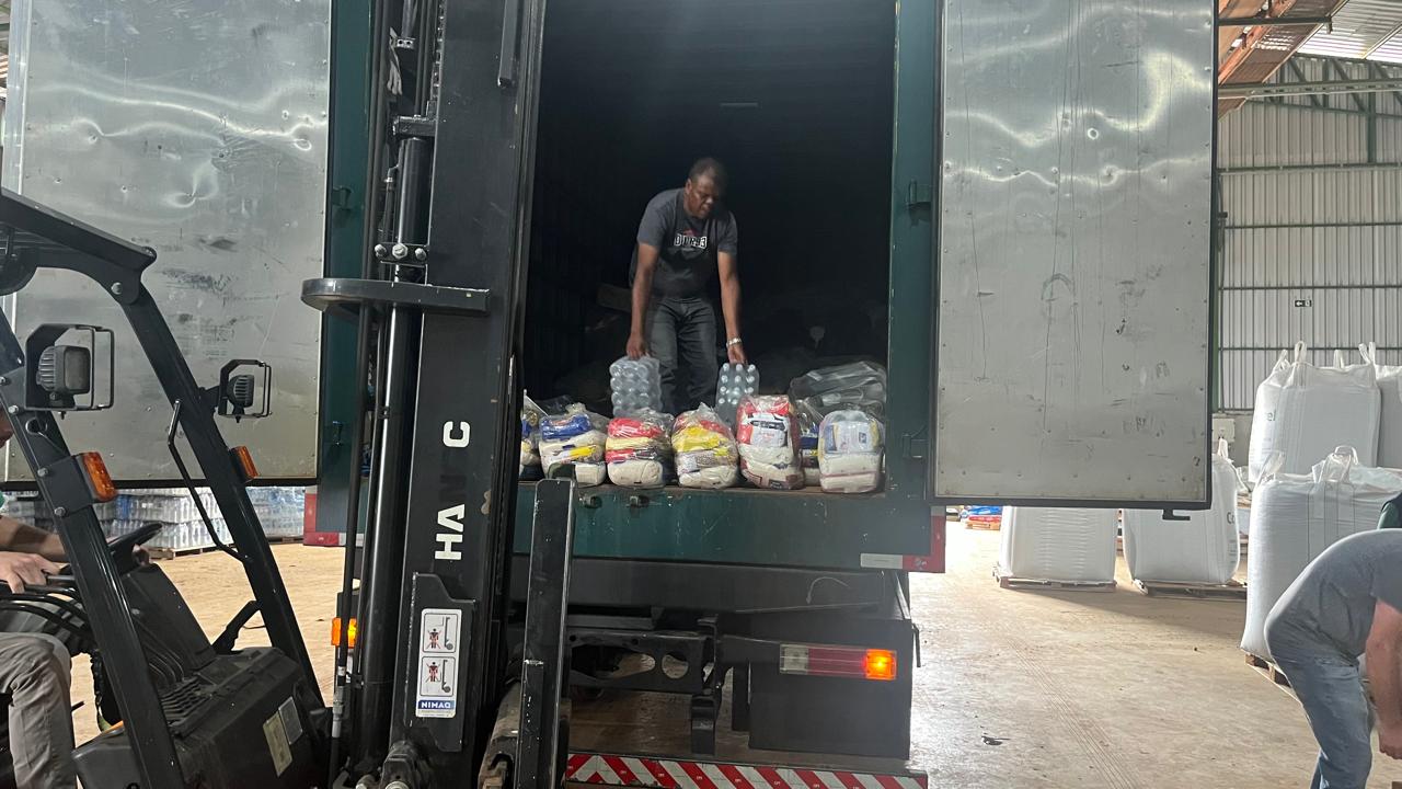 Homem descarrega doações de dentro de um caminhão baú