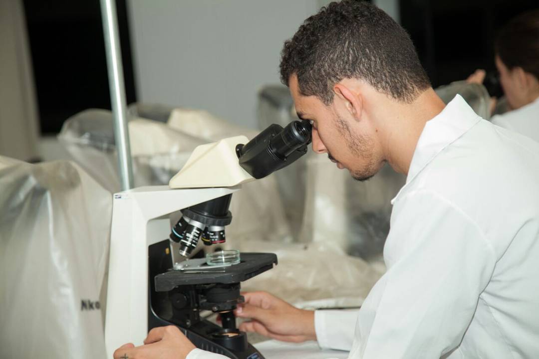 Bruno utiliza microscópio em laboratório